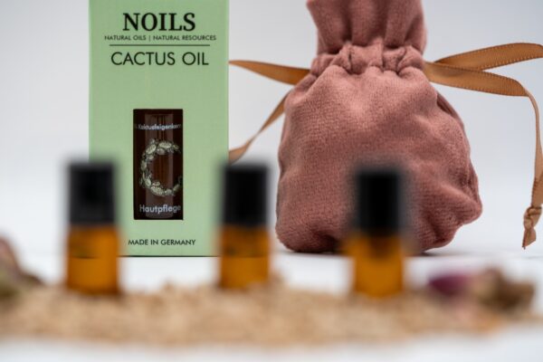 Noils Cactus Oil Verpackung mit rosa Samtbeutel und kleinen Ölfläschchen im Vordergrund