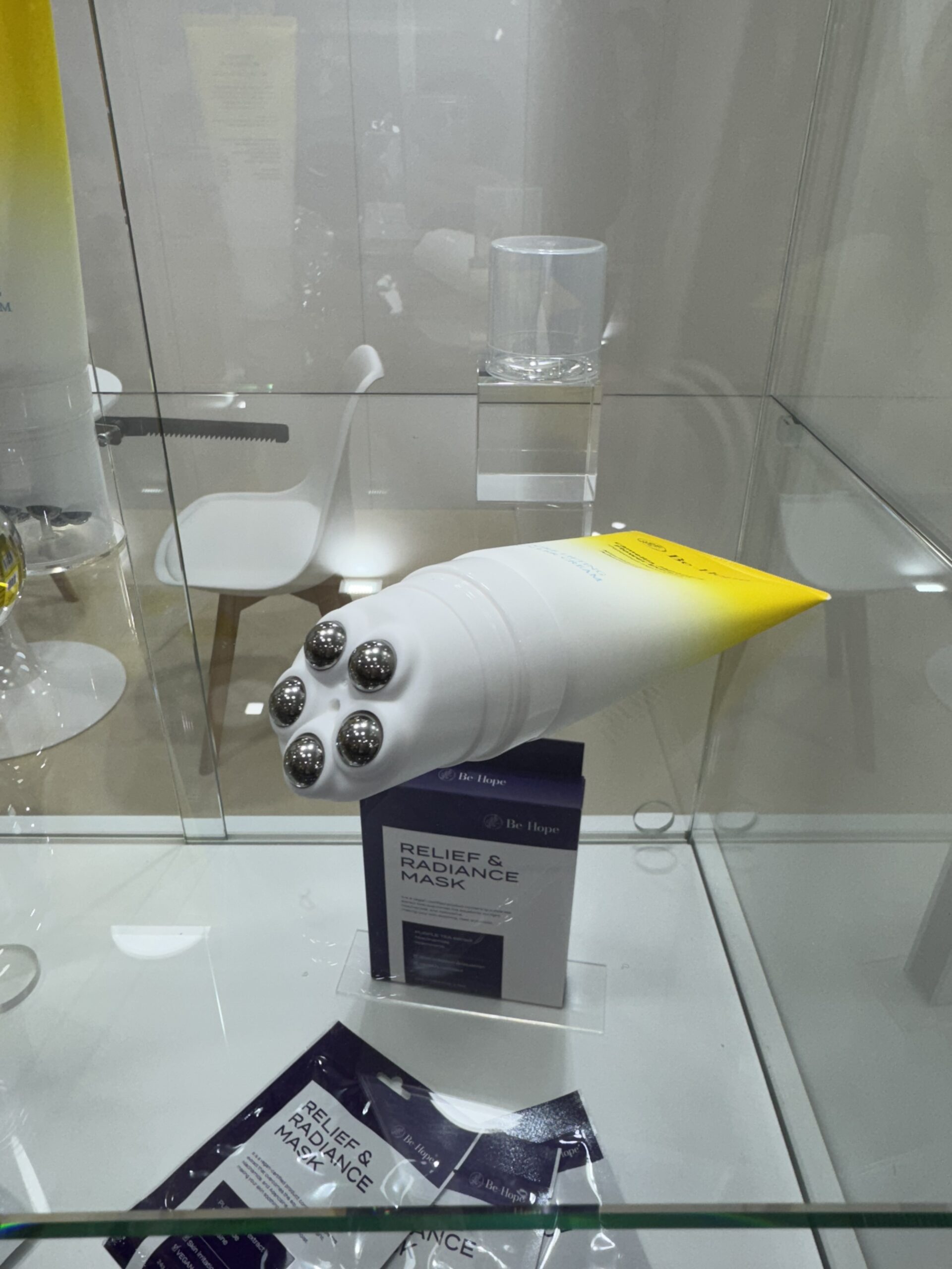 Innovative koreanische Kosmetiktube mit integrierten Massagekugeln, präsentiert auf der Cosmoprof Bologna 2025 in einer gläsernen Vitrine.